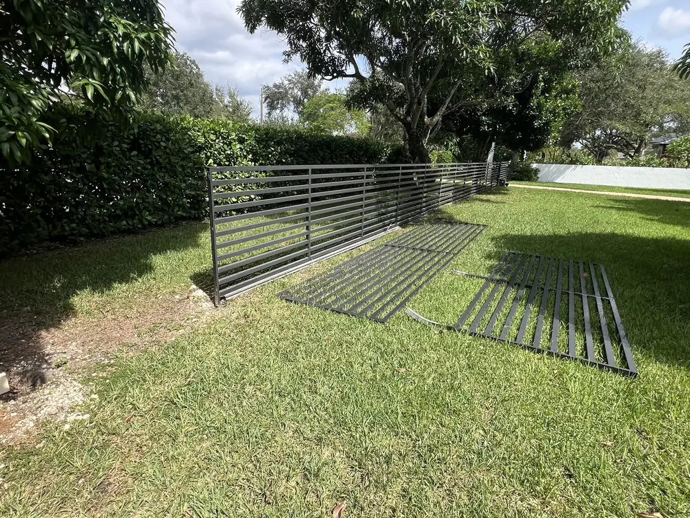 New gate panels laid out on the grass before hanging, alongside the matching run of horizontal slat fence