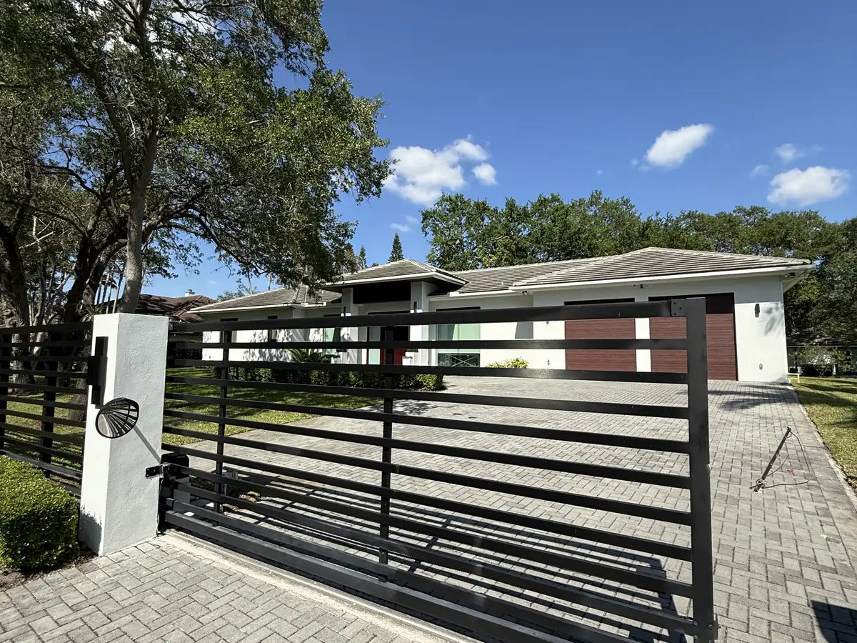 Dark horizontal slat aluminum slide gate drawn across a paver driveway at a single storey contemporary home