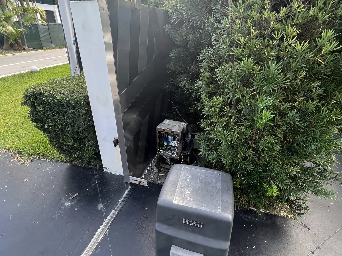 Slide gate operator at the edge of a driveway with the gate panel drawn back alongside it