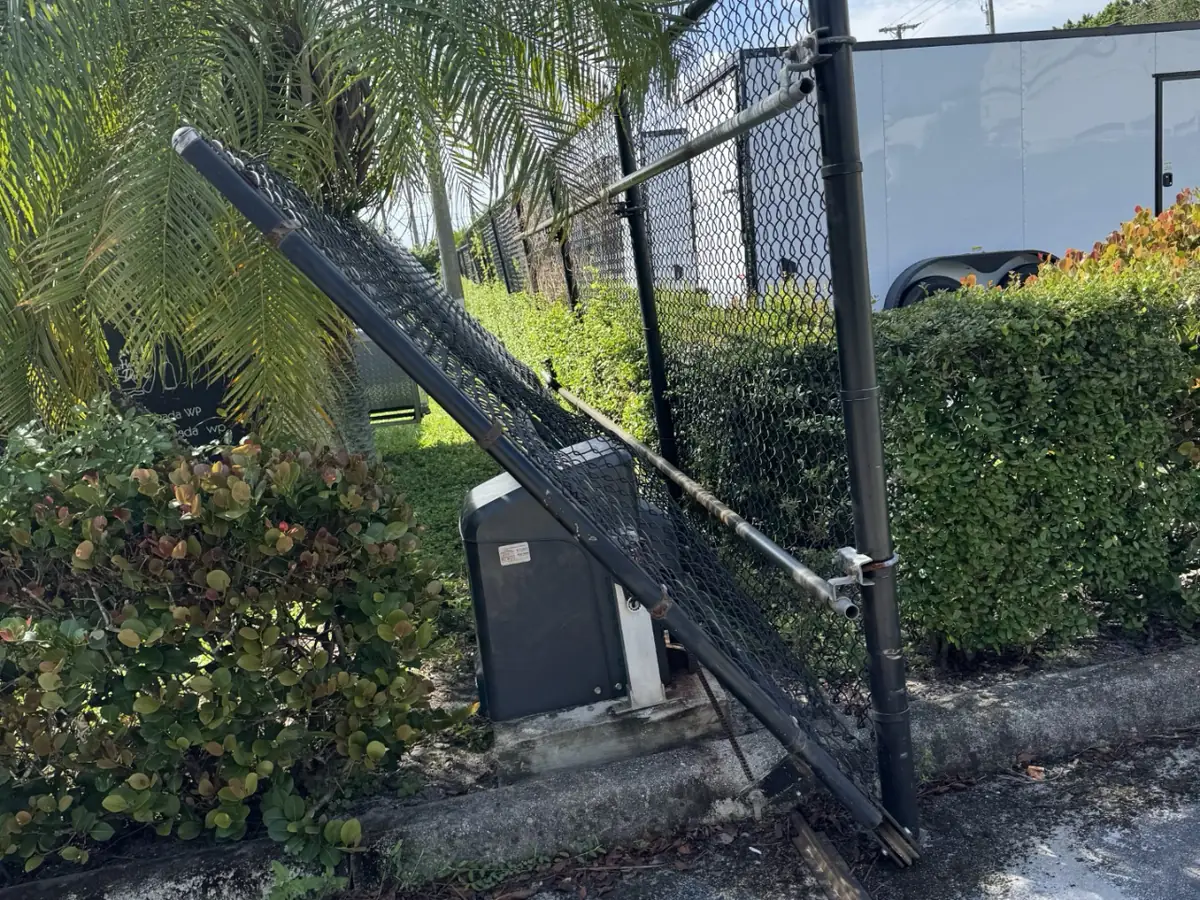 Swing arm gate operator mounted on its post beside a chain link fence at a commercial yard