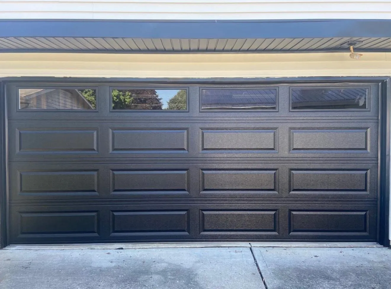 Dark modern sectional garage door installed on a Miami home