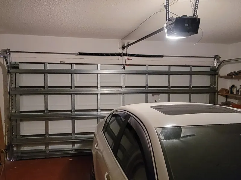 Garage door opener installed on the rail above a door with a car parked below