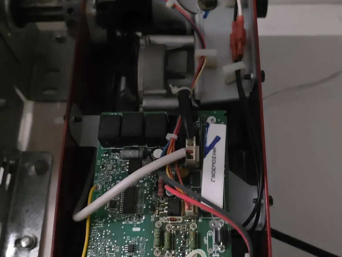 The logic board of a garage door opener with its cover off, exposed for a circuit repair