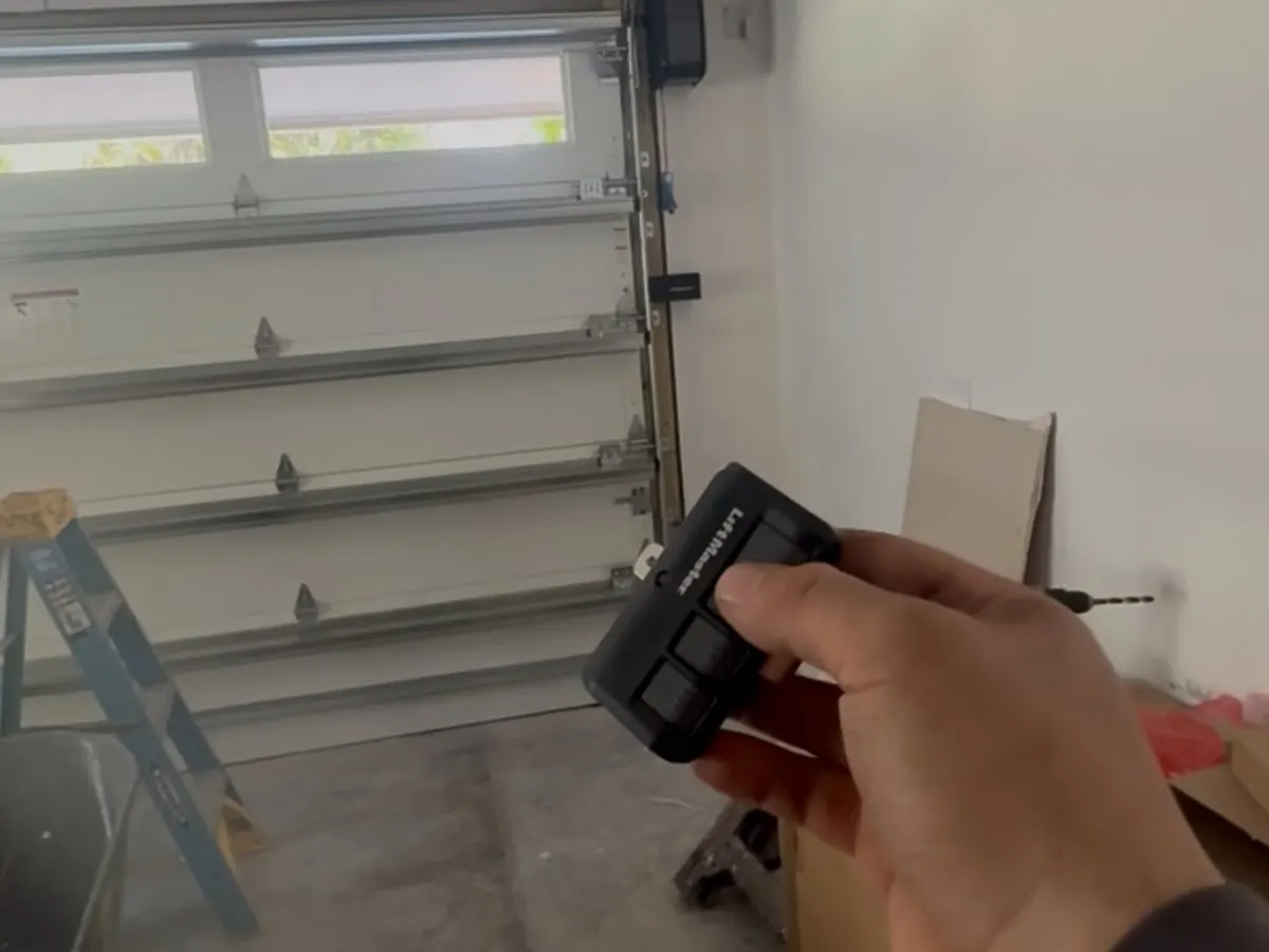 A CMC technician testing a LiftMaster remote in front of a closed white garage door after a service call