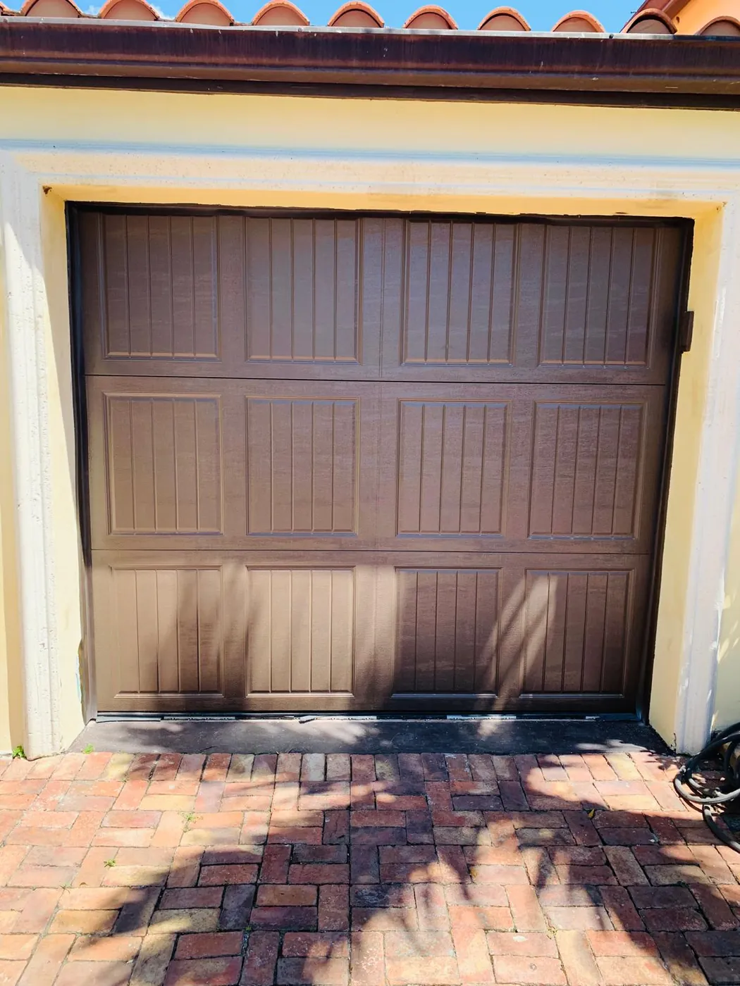 Brown raised-panel garage door above a paver driveway in Miami-Dade