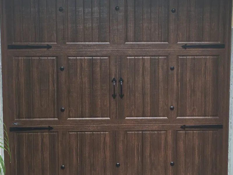 Walnut carriage house single garage door with decorative hardware
