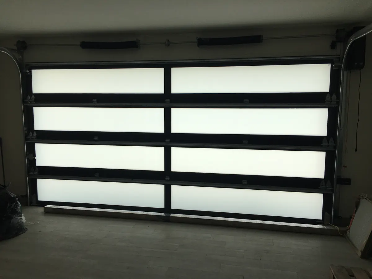 A frosted glass garage door in a black frame seen from inside the garage, daylight coming through the panels