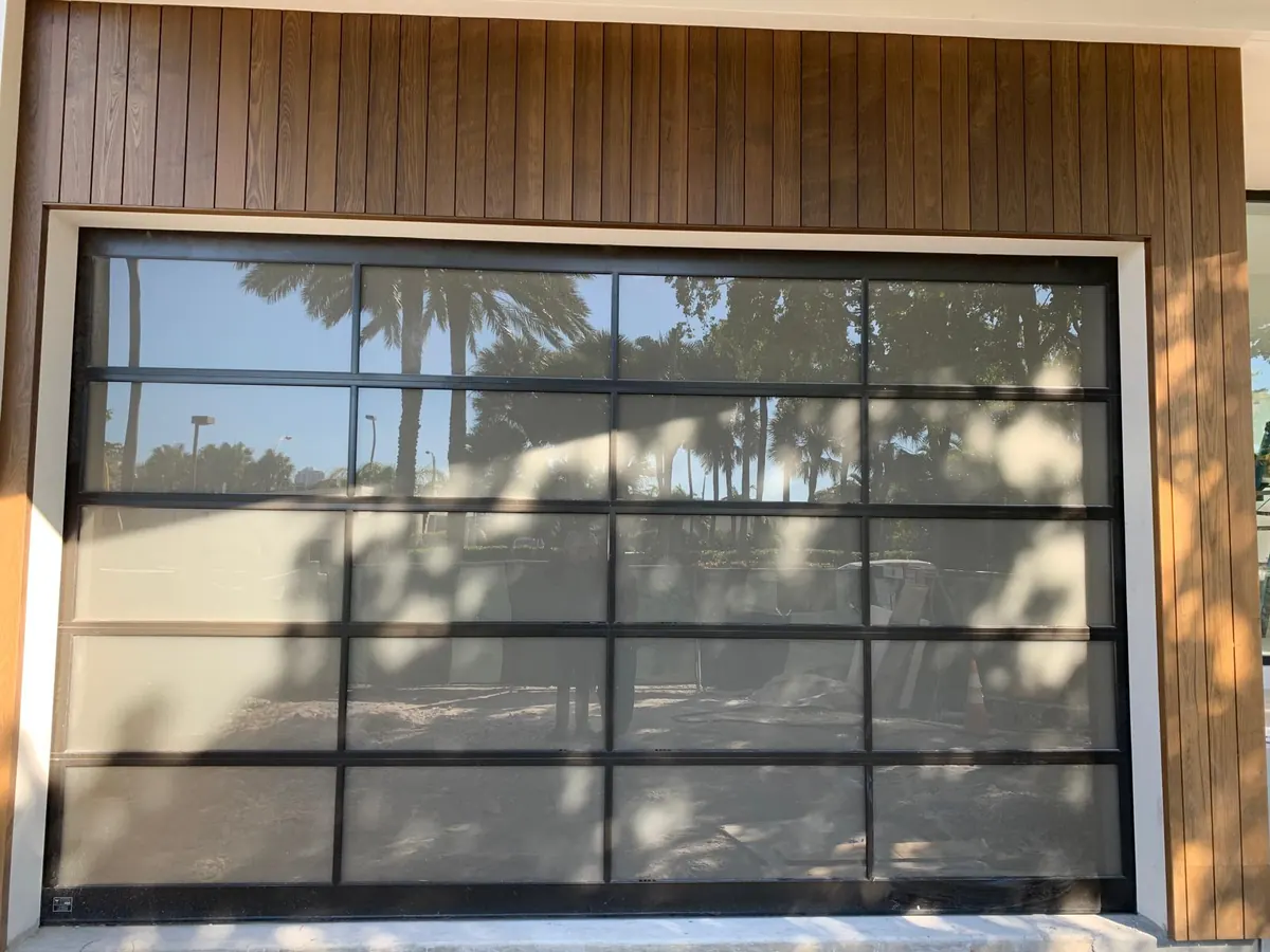 Full view glass garage door in a black frame below a wood clad upper storey