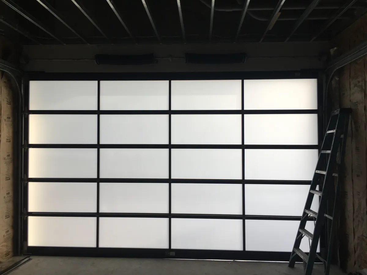 Full view frosted glass garage door seen from inside the garage during installation, with the stepladder still in the bay