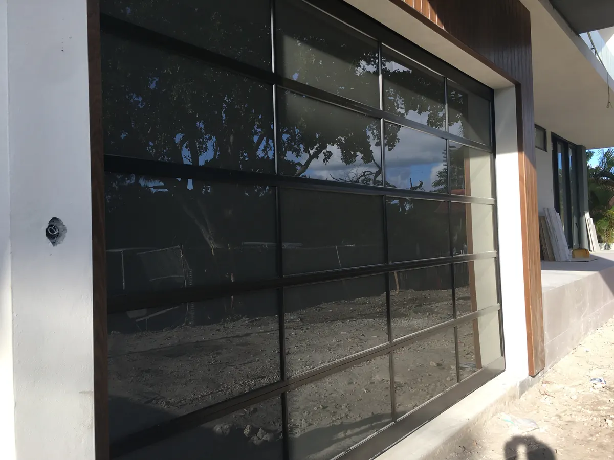 A tinted full view glass garage door in an aluminium frame on a house still under construction