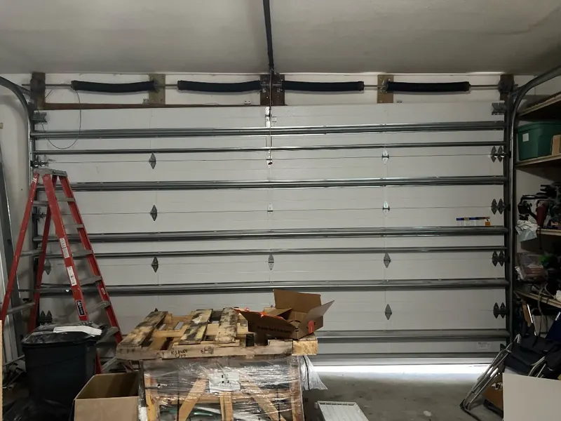 Interior de una puerta de garaje doble blanca de panel liso con sus refuerzos y herrajes