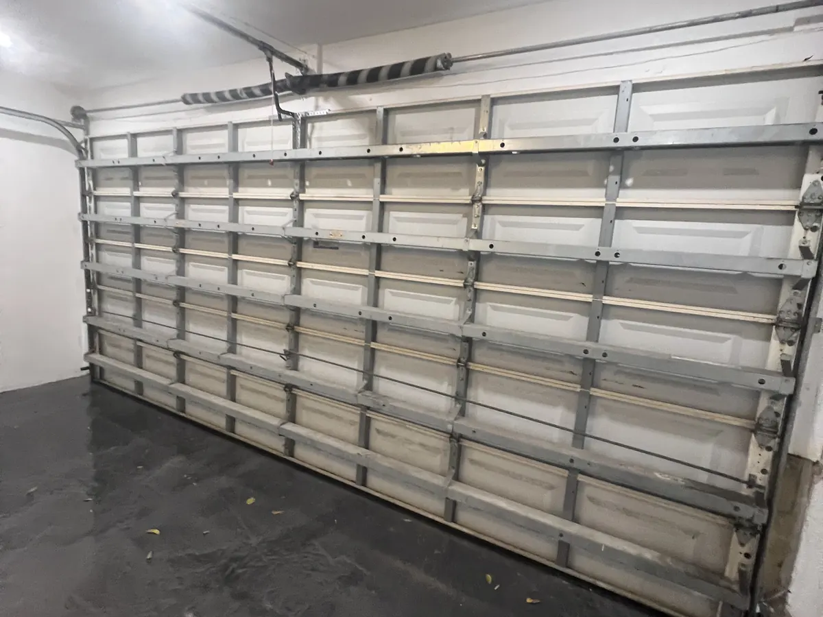 The inside face of a double car garage door showing the reinforcing struts, the torsion shaft and the track