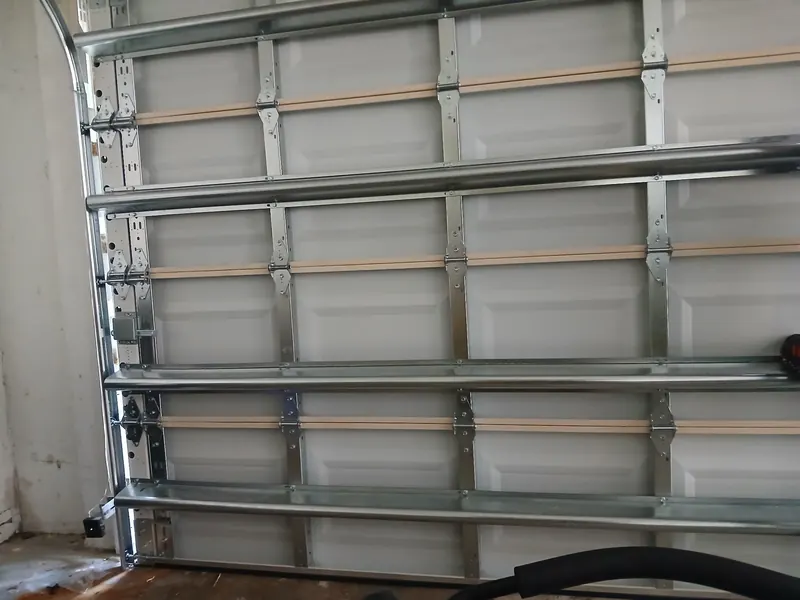 Inside view of a new white garage door with reinforcing struts and vertical tracks