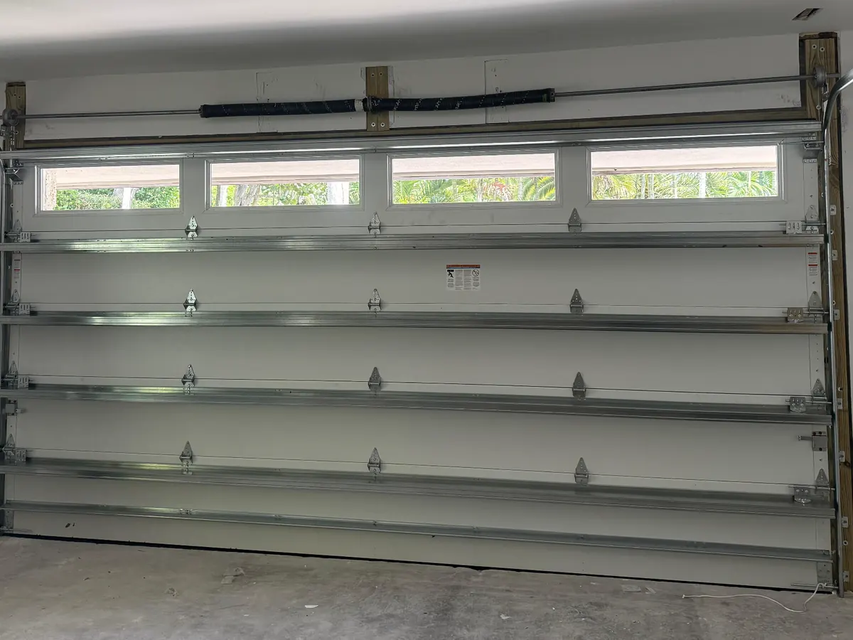 The inside face of a white garage door with a window row across the top section and the reinforcing struts below