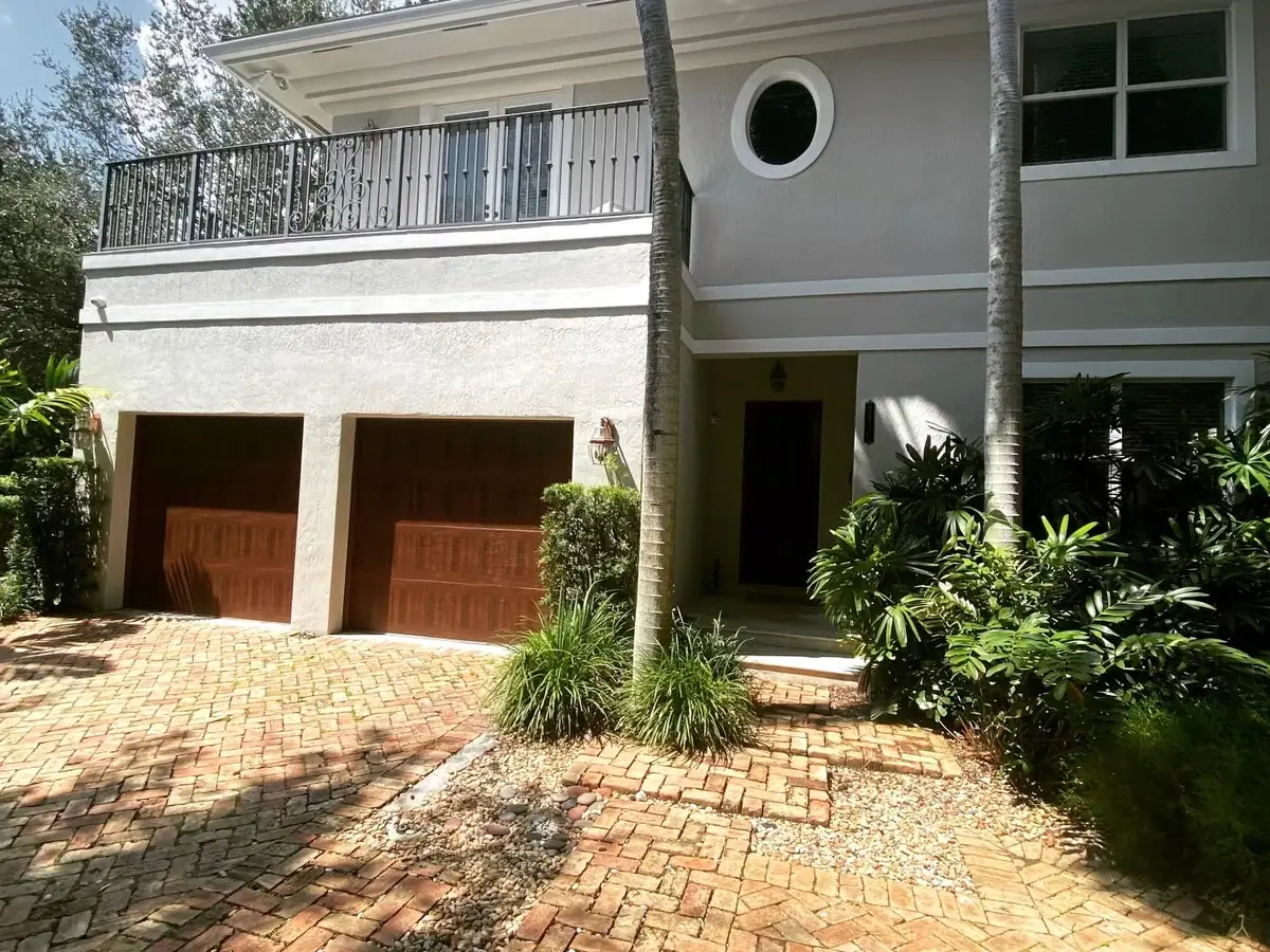A pair of single car raised panel doors in a mahogany finish on a two storey home with a brick paver drive