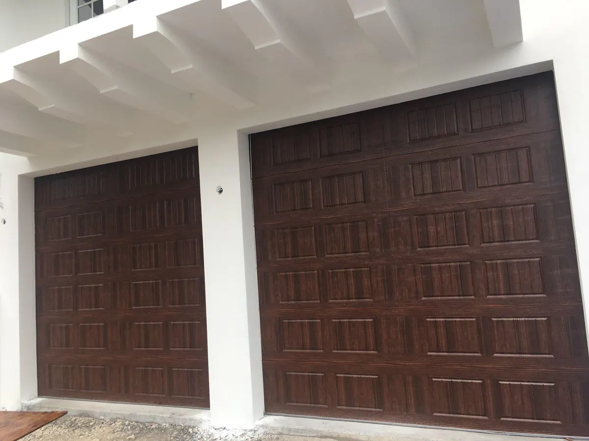 Walnut woodgrain raised panel double garage door below a white pergola, with the single bay alongside it