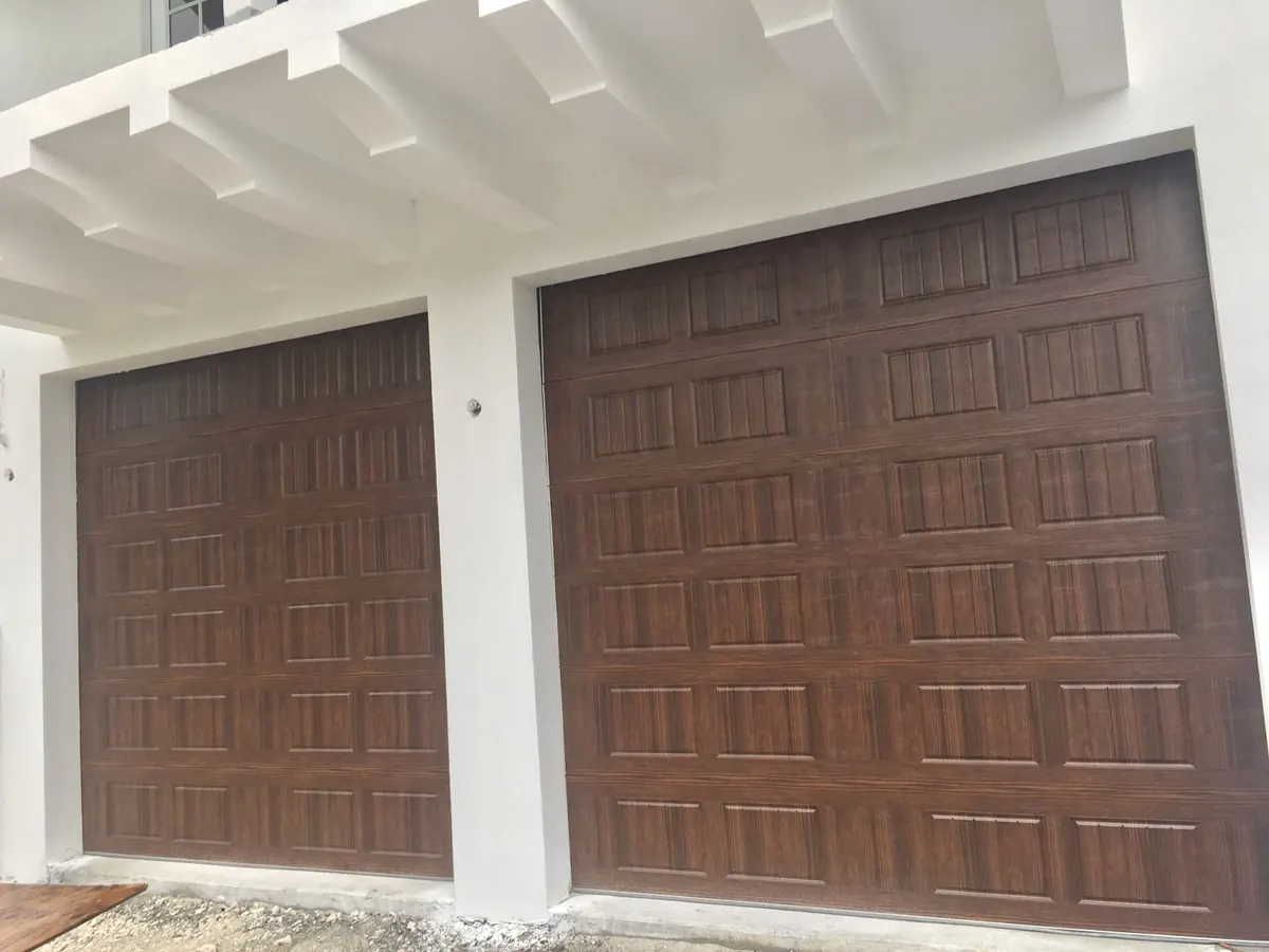 Two walnut woodgrain raised panel garage doors under a white pergola across the front of the garage