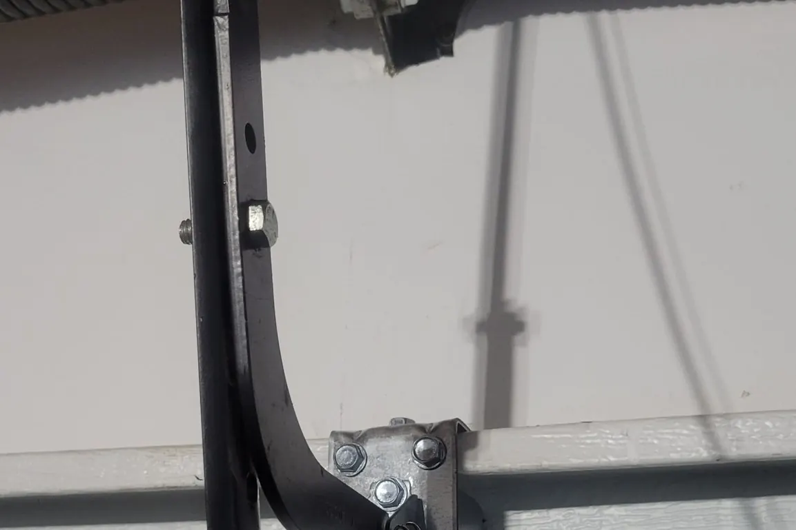 A garage door roller seated in its track at the hinge bracket, seen from inside the garage