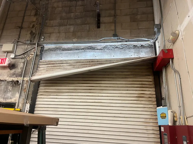 Damaged bottom bar on a rolling steel door before repair