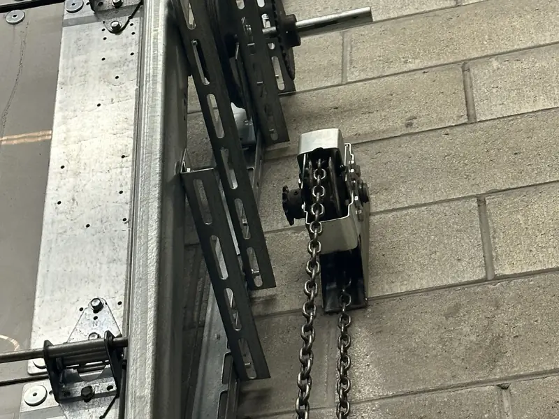 Close-up of the chain hoist and mounting brackets fitted at the end of a commercial rolling door against a block wall