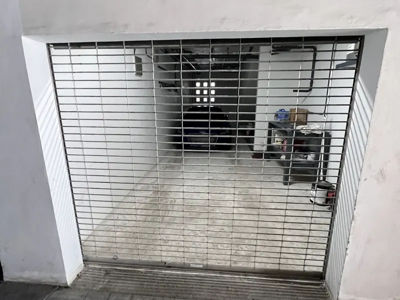 Steel rolling grille closed across a garage entrance with a car parked behind it