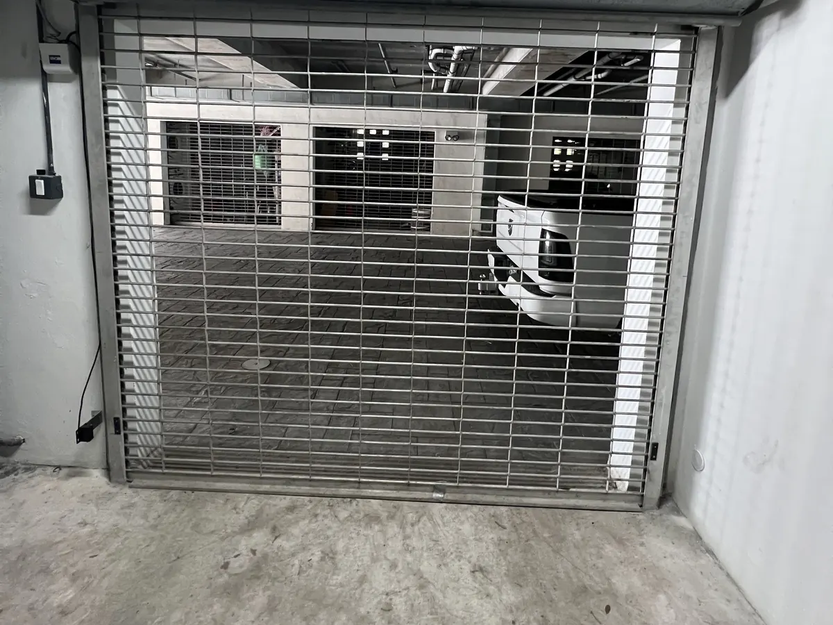 A galvanised rolling grille closed across a parking garage entrance