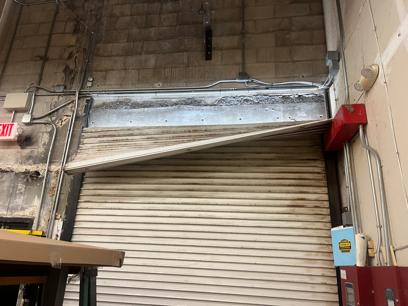 Damaged hood and curtain on a commercial rolling door before repair