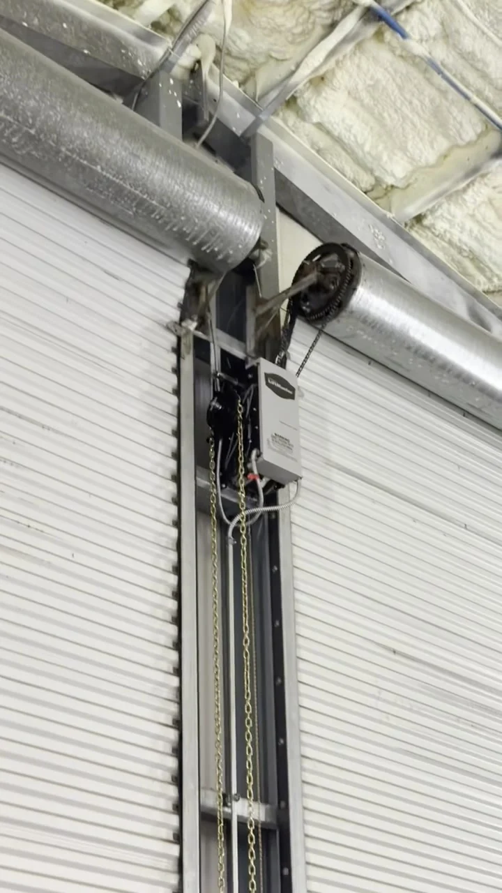 Rolling steel door operator and chain hoist mounted at the head of the opening