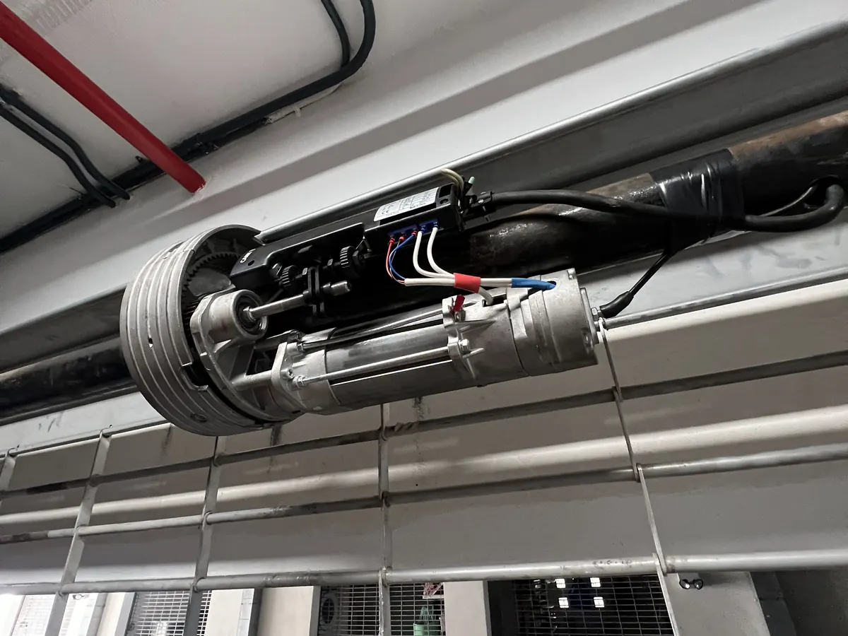 A shaft mounted rolling door operator and its drive chain above a parking garage entrance