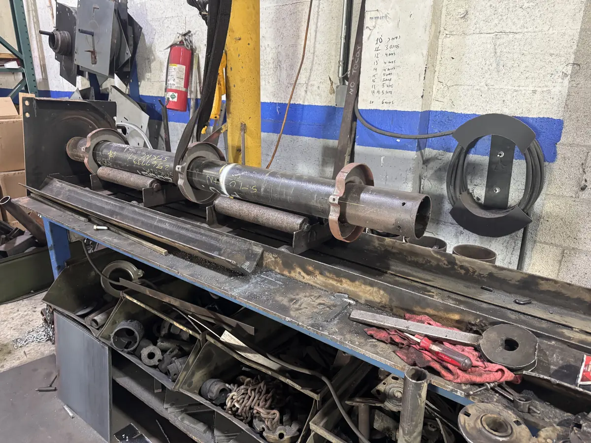 A rolling door shaft and coupling assembly laid out on the workshop bench before fitting