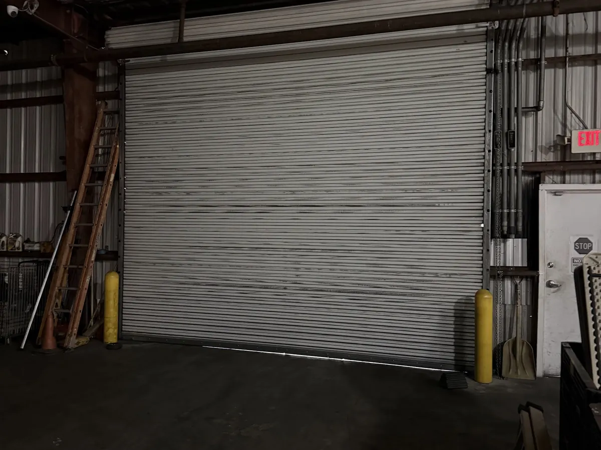 A galvanised rolling steel door closed to the floor inside a metal framed building
