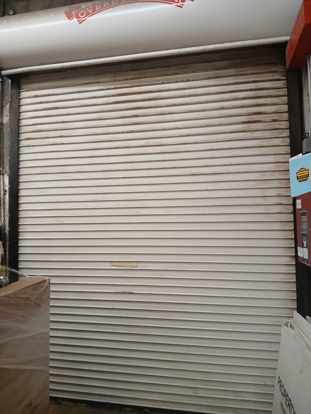 White slat rolling door closed inside a storefront, fitted by CMC Door Service