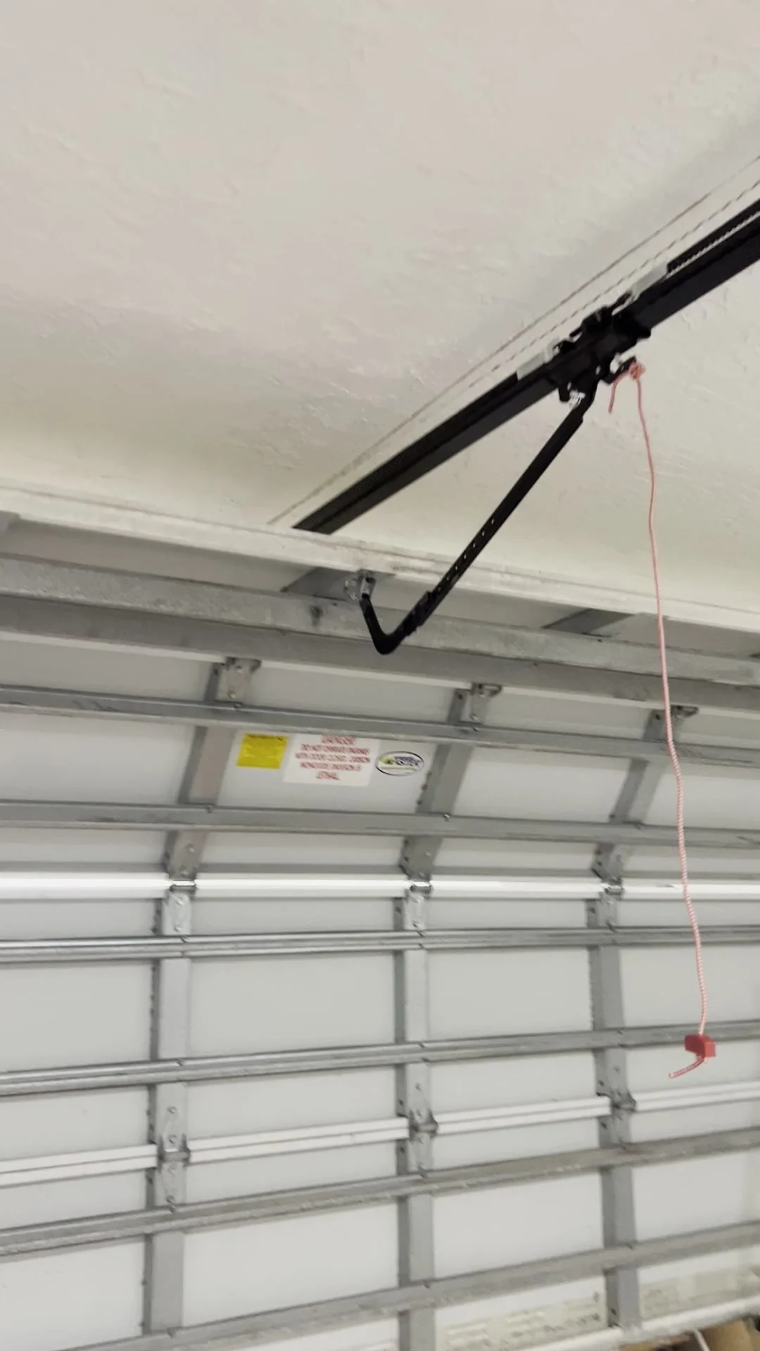 White sectional garage door from inside with the opener arm and rail fitted