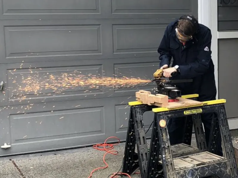 Técnico de CMC cortando acero en el sitio durante una reparación de puerta de garaje