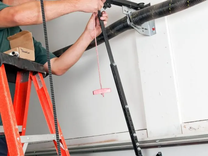 CMC technician on a ladder servicing a torsion spring assembly