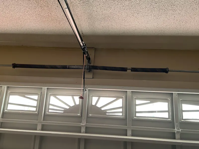 Torsion springs and center bearing plate mounted above a sectional garage door with sunburst window inserts