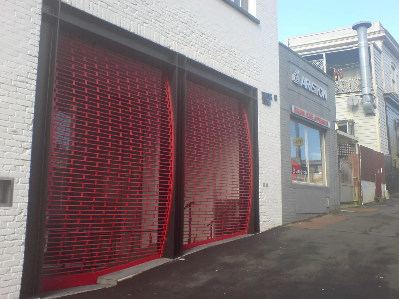 Bright red rolling security grilles closed across a commercial frontage