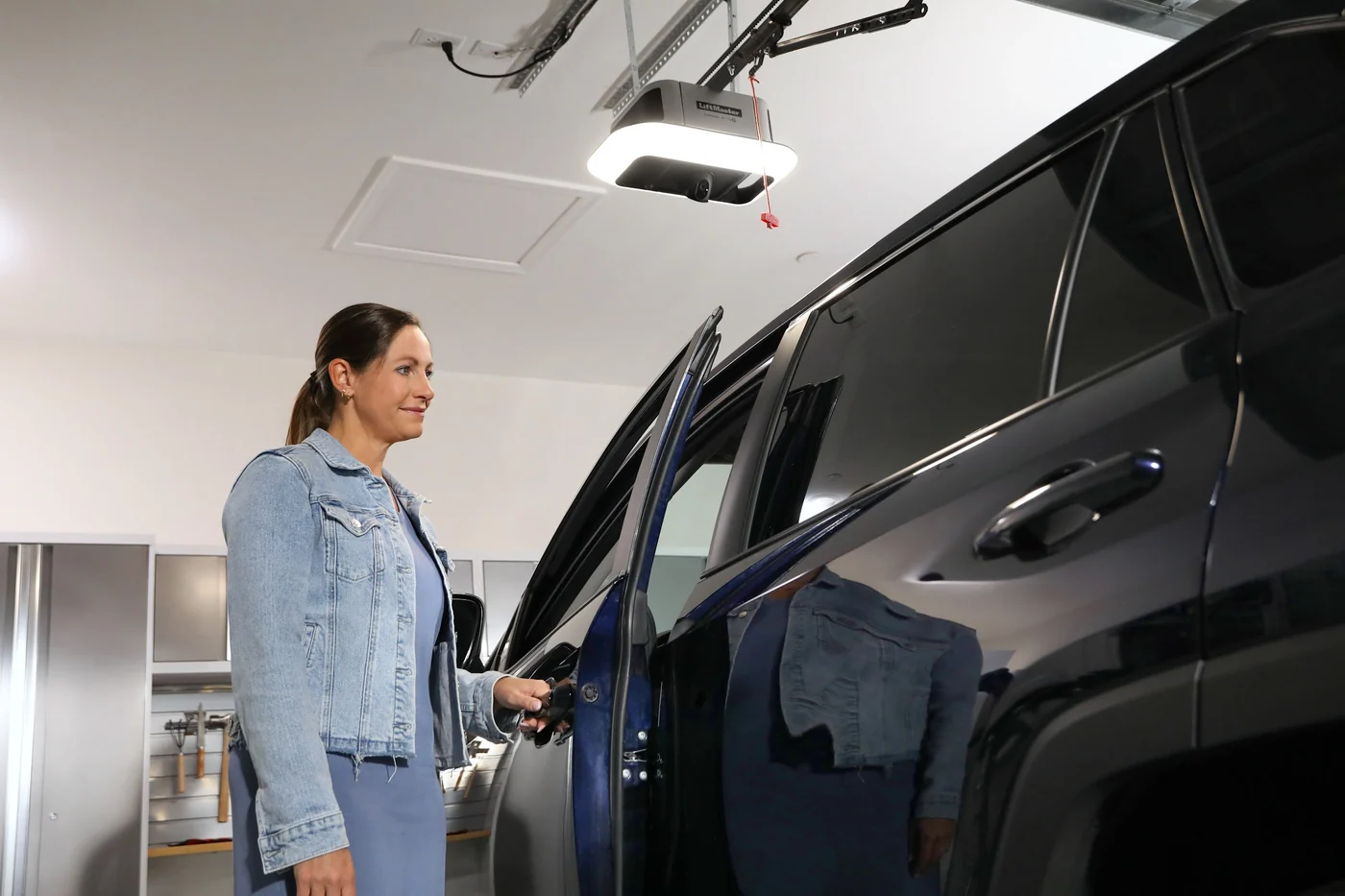 Driver getting into her car in a garage lit by the LED panel of a LiftMaster opener