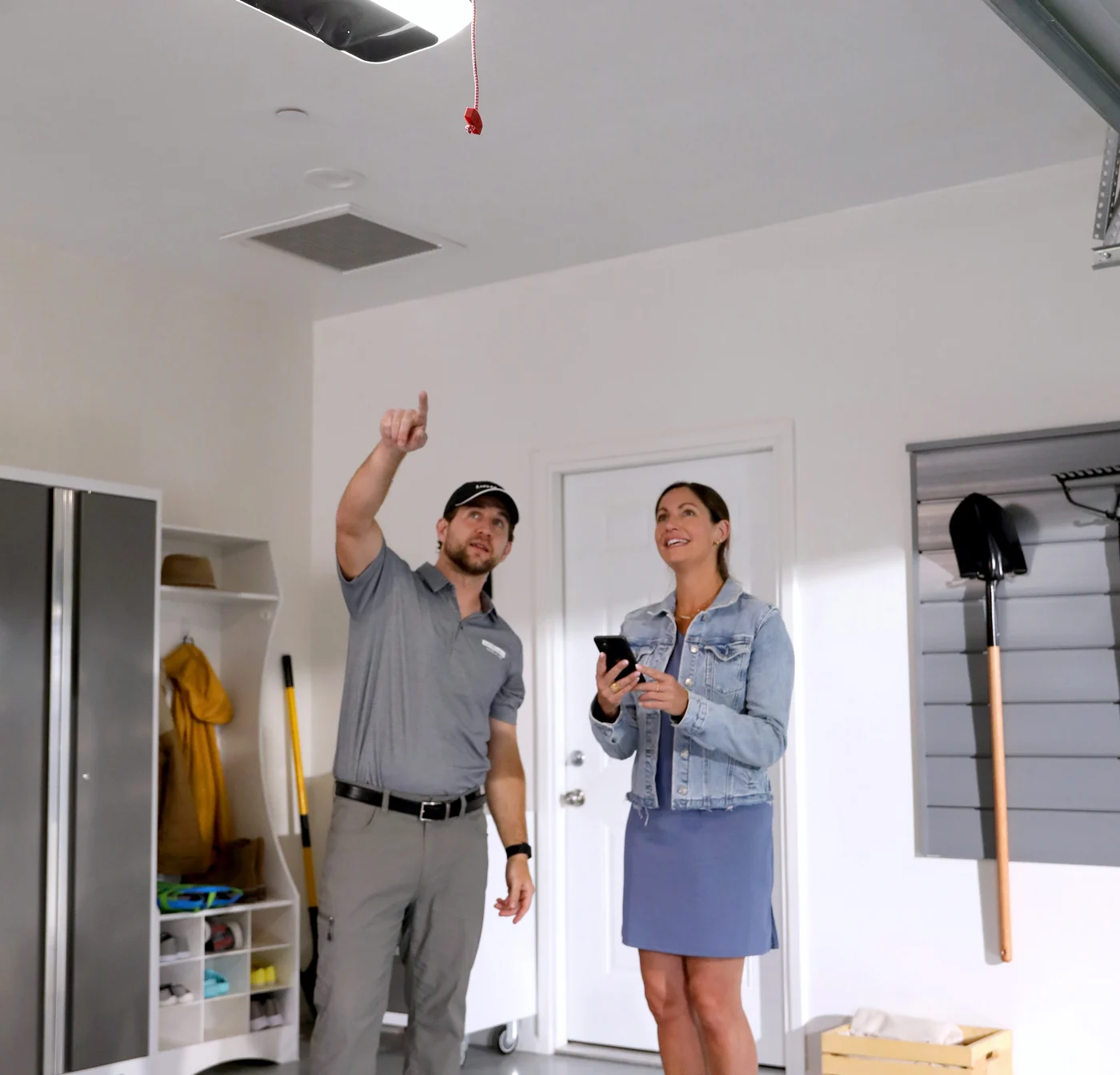 Technician handing a finished LiftMaster opener over to the homeowner in her garage