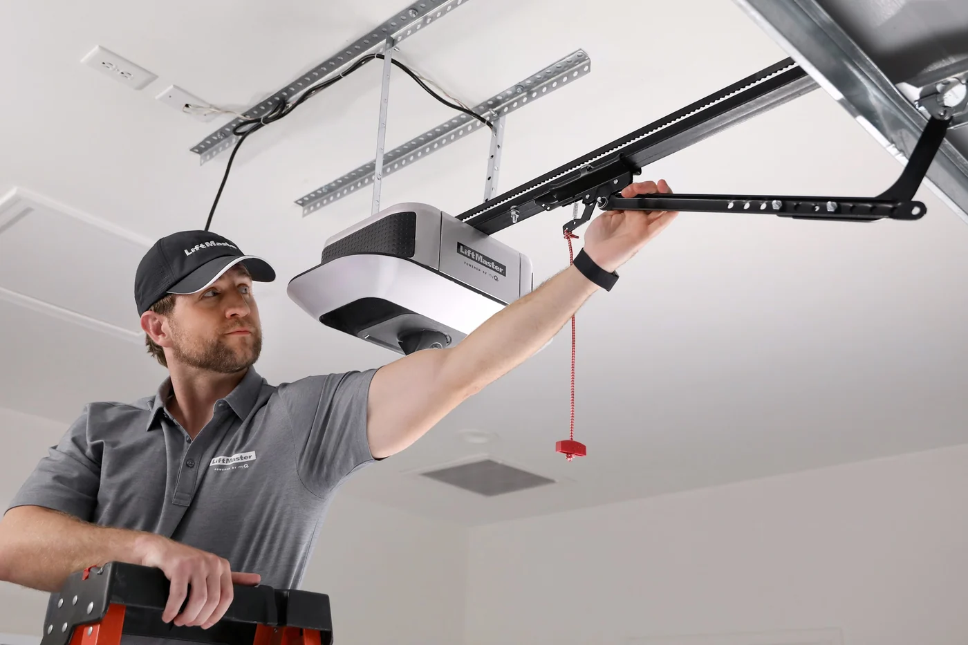 Technician fitting the rail of a LiftMaster belt drive opener to a garage ceiling