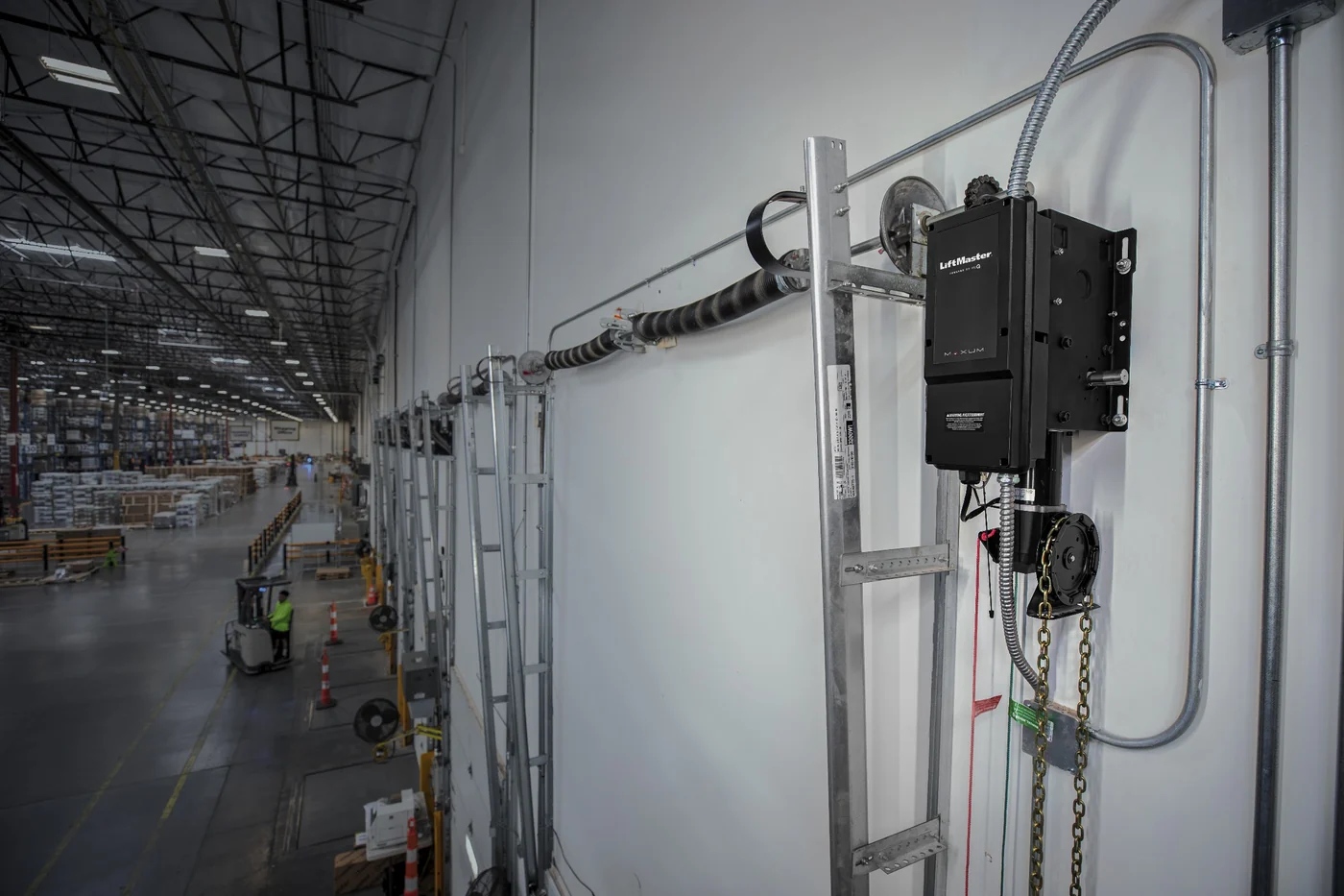 LiftMaster Maxum jackshaft operator mounted beside a warehouse dock door, with the chain hoist and control station