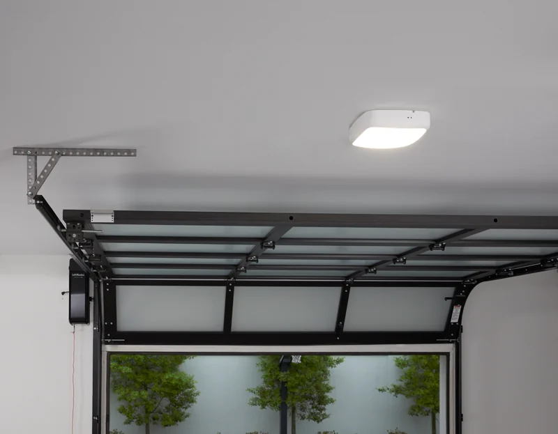 Garage interior with a full view glass door open and a myQ smart control unit on the ceiling