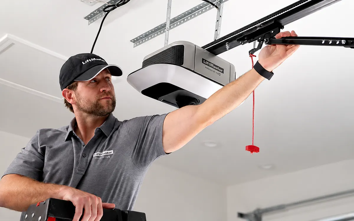 Técnico en una escalera instalando un motor de puerta de garaje LiftMaster myQ en su riel de techo