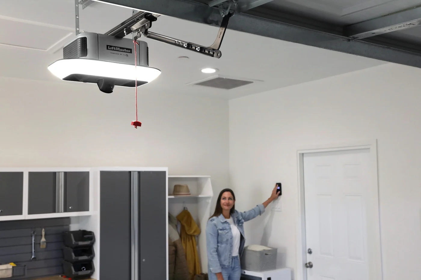 Homeowner using the wall control in a tidy garage with a LiftMaster opener overhead