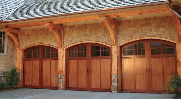 Cream arched carriage house garage doors on a stone home