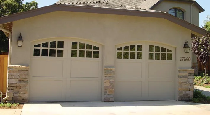 An arched wood garage door in a stone opening