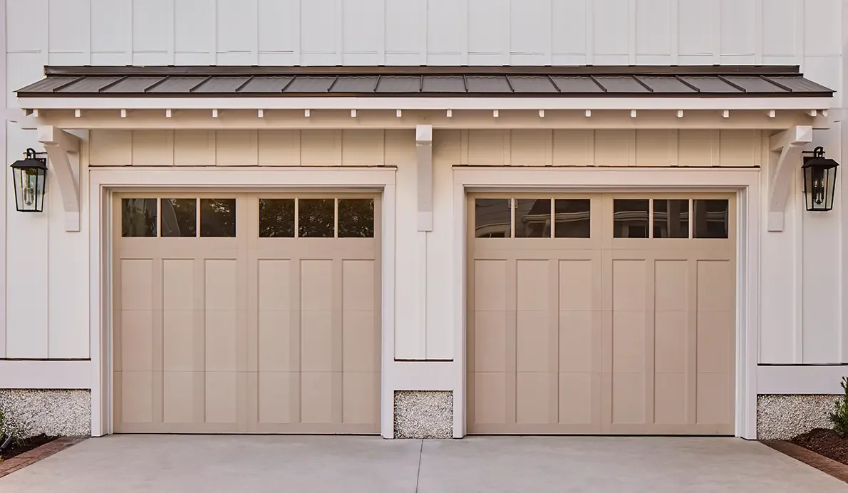 Two tan carriage house garage doors with decorative hardware