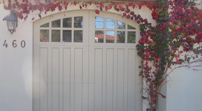 A wood carriage garage door under a barrel tile roof