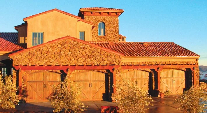 An arched carriage garage door framed by climbing vine