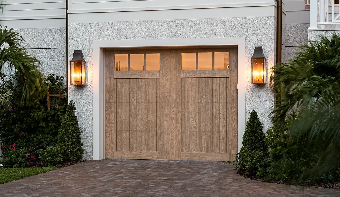 A wood carriage house garage door between two lanterns